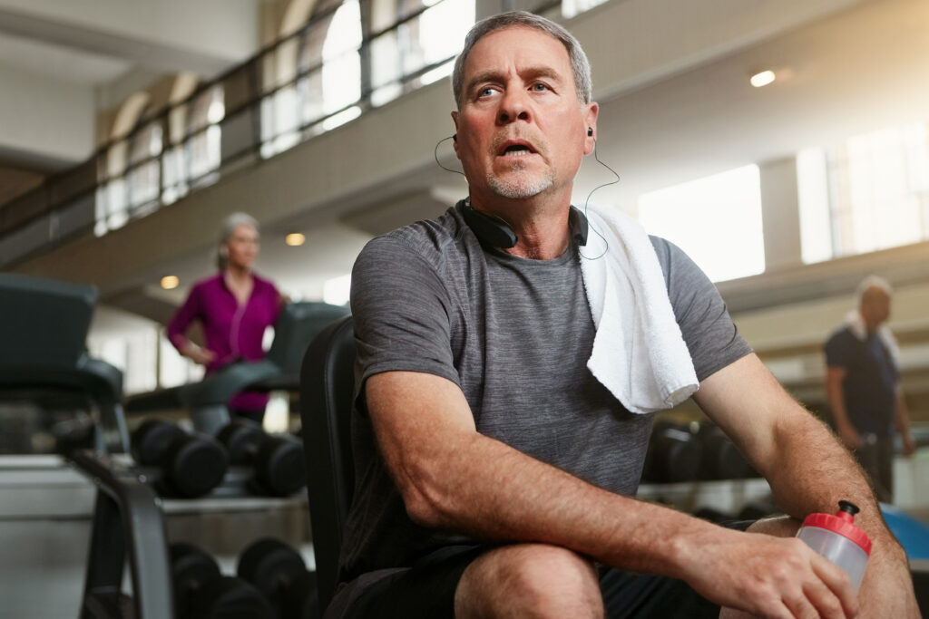 A man at the gym looking tired during a workout.